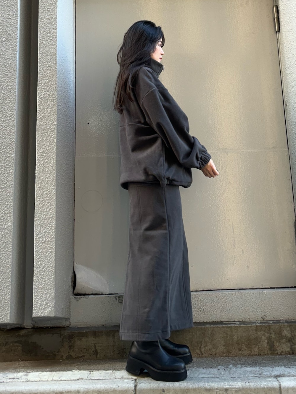 グレー系のTシャツ/カットソー、グレー系のスカート、ブラック系のブーツを着用したレディースの秋コーディネートの2枚目の写真