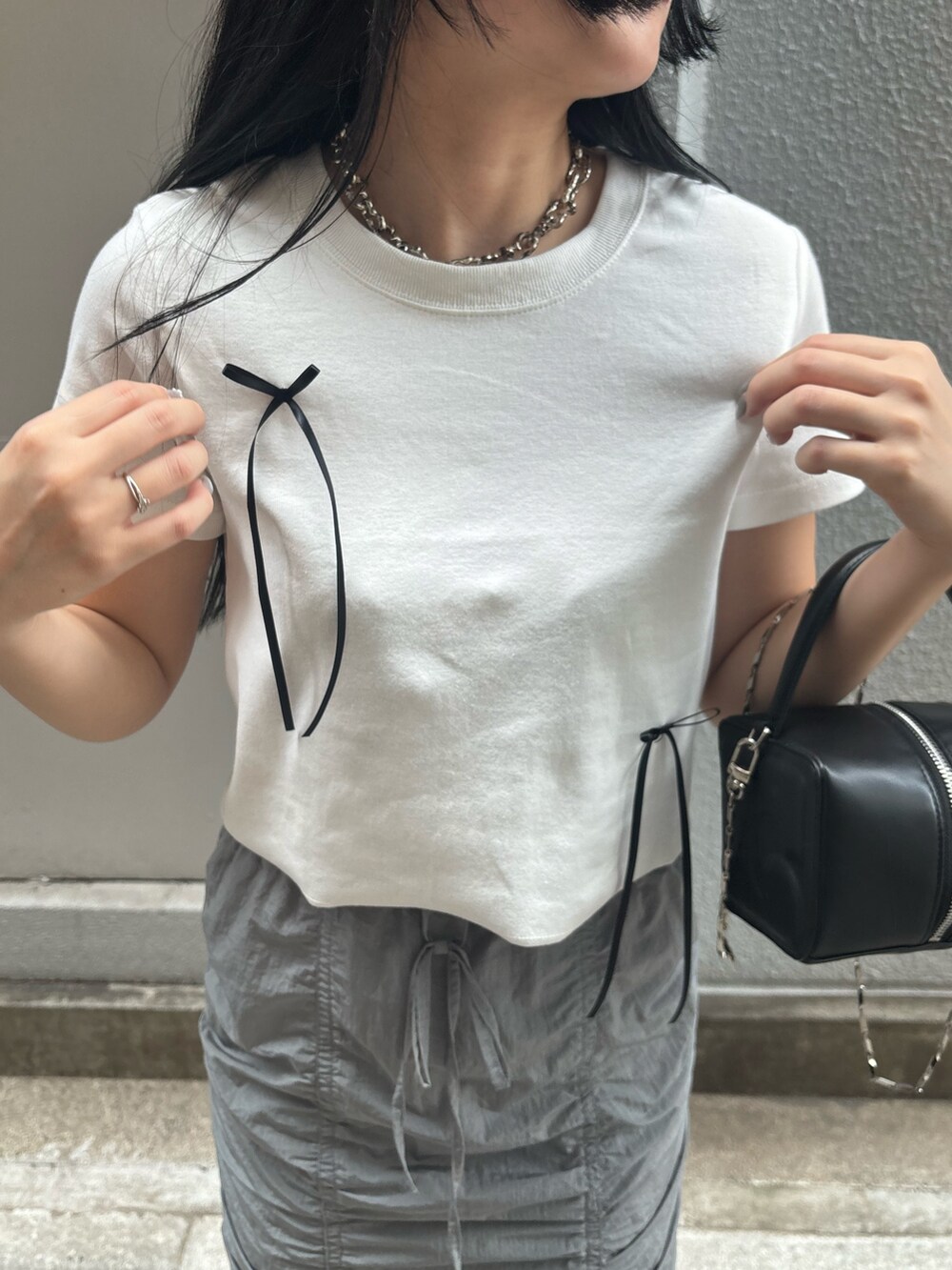 ブラック系のサンダル、ホワイト系のTシャツ/カットソー、ブラック系のハンドバッグを着用したレディースの夏コーディネートの4枚目の写真