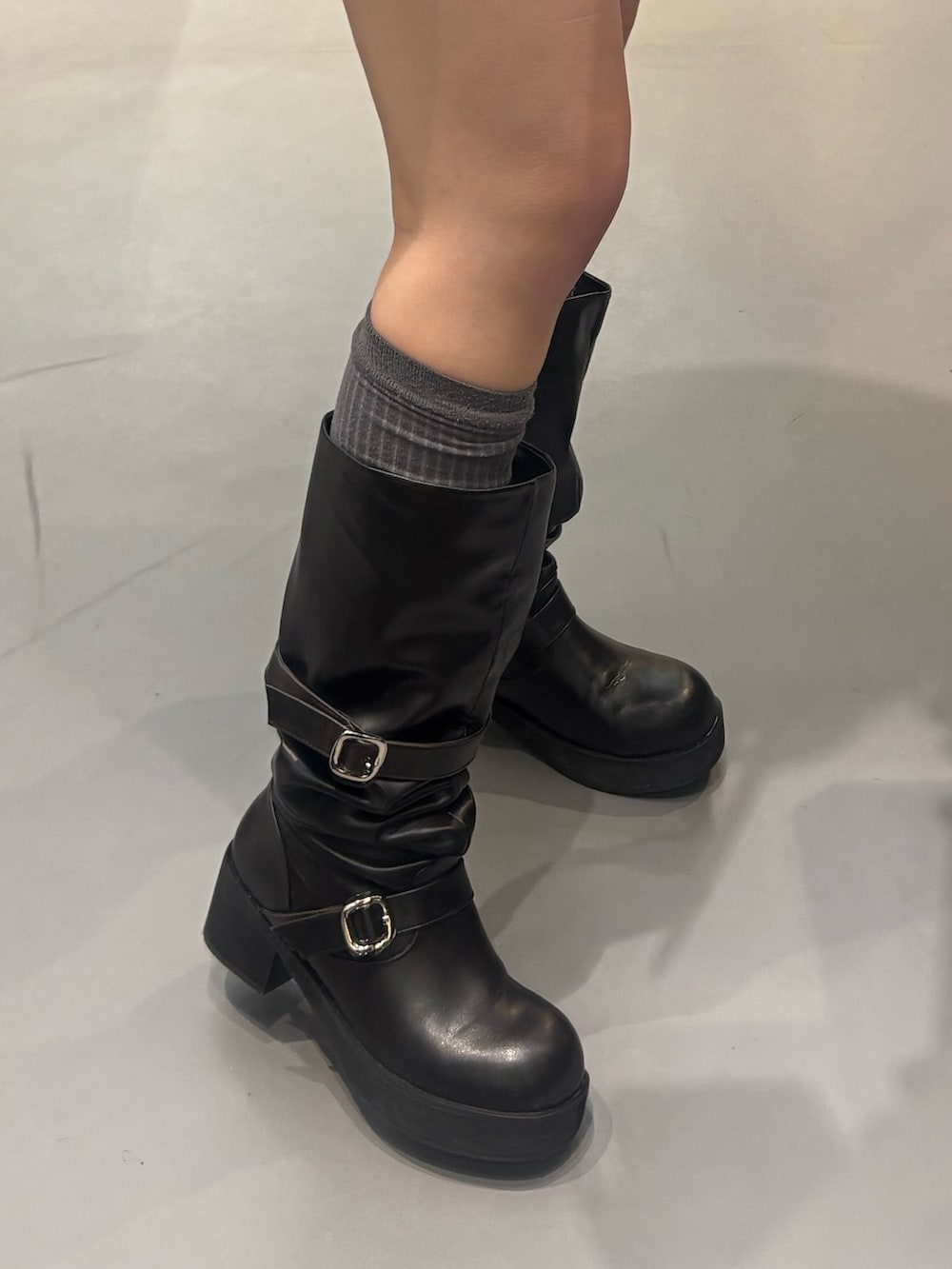 ブラック系のブーツ、グレー系のスカート、ブラック系のニット/セーターを着用したレディースの冬コーディネートの5枚目の写真