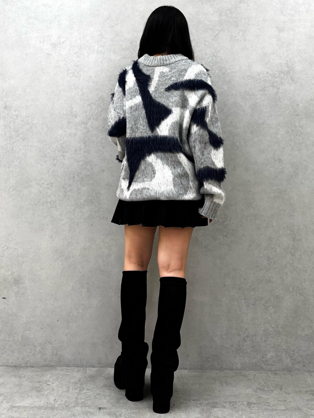 ブラック系のブーツ、ブラック系のスカート、グレー系のニット/セーターを着用したレディースの秋コーディネートの3枚目の写真