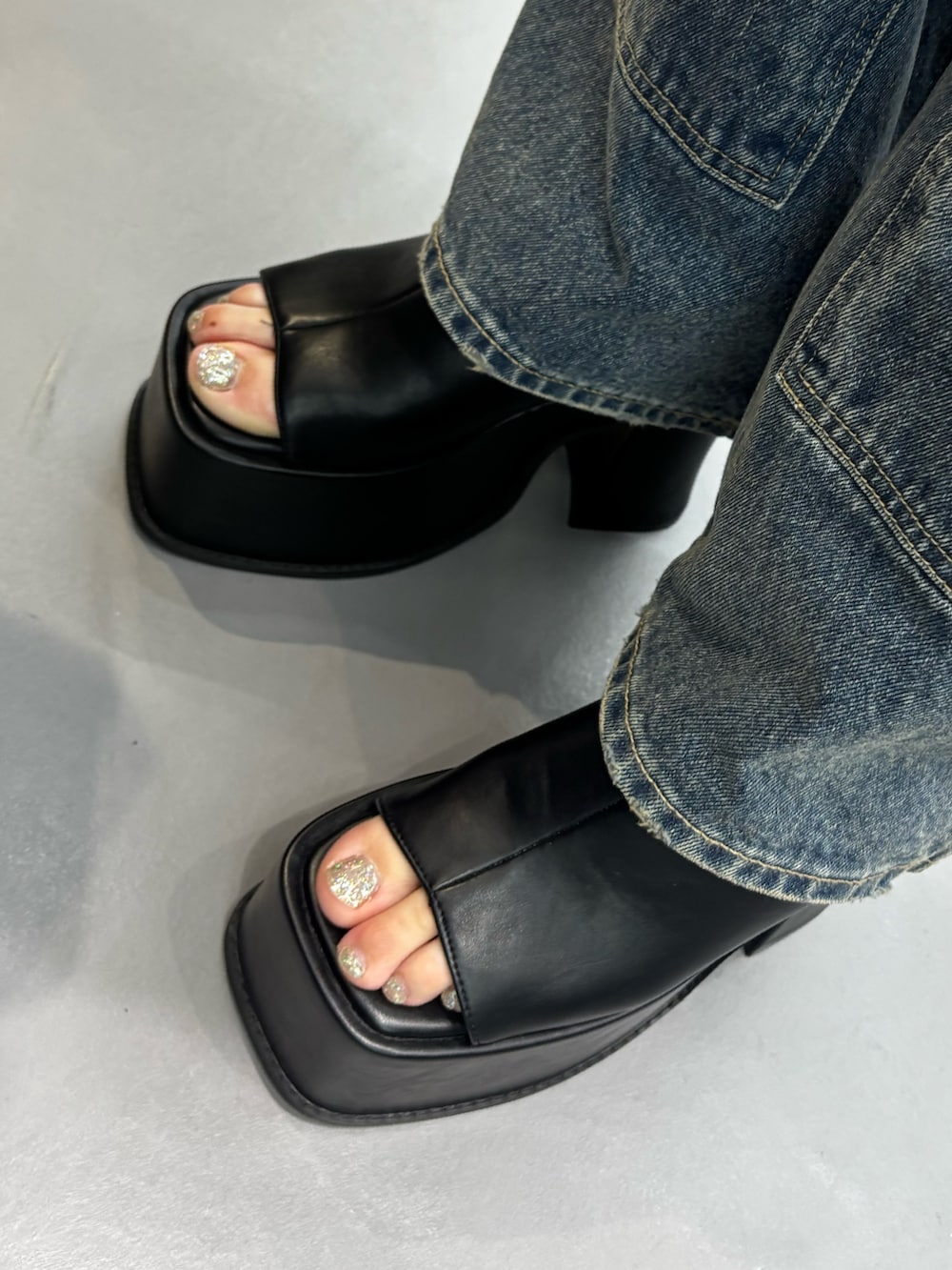 ブラック系のサンダル、ブルー系のデニムパンツ、ブラック系のTシャツ/カットソーを着用したレディースの春コーディネートの5枚目の写真