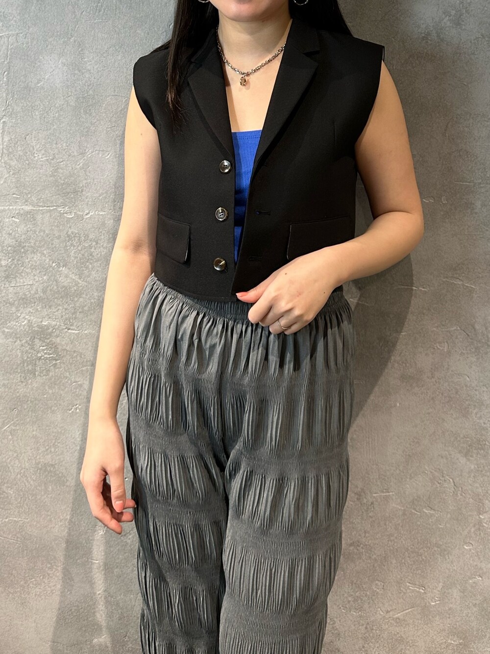 グレー系のその他パンツ、ブラック系のベスト、ブルー系のキャミソールを着用したレディースの春コーディネートの4枚目の写真