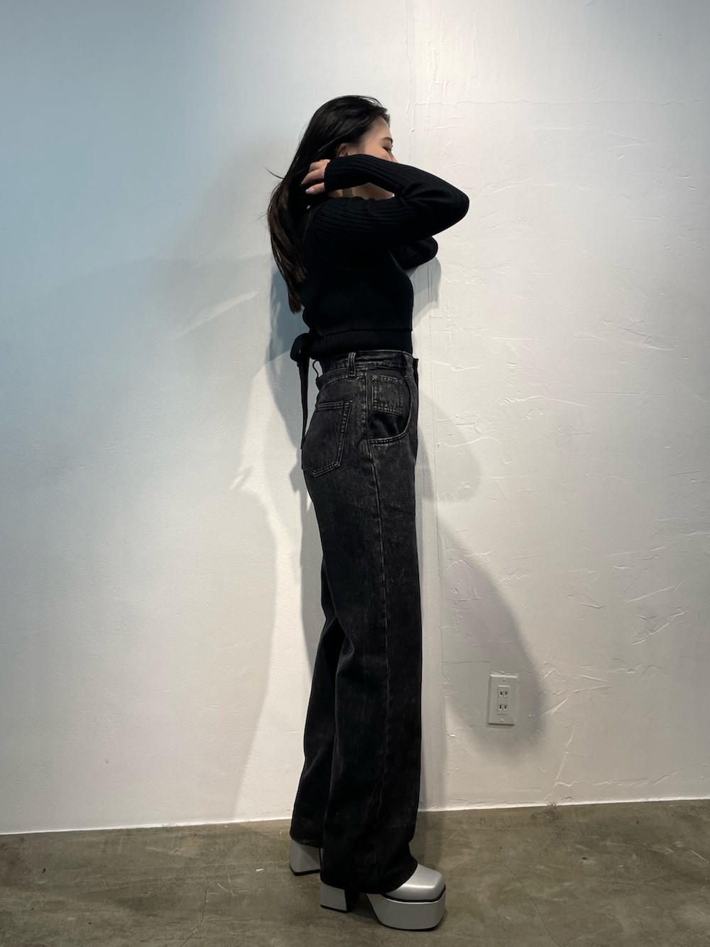 ブラック系のデニムパンツ、ブラック系のニット/セーター、シルバー系のブーツを着用したレディースの秋コーディネートの2枚目の写真