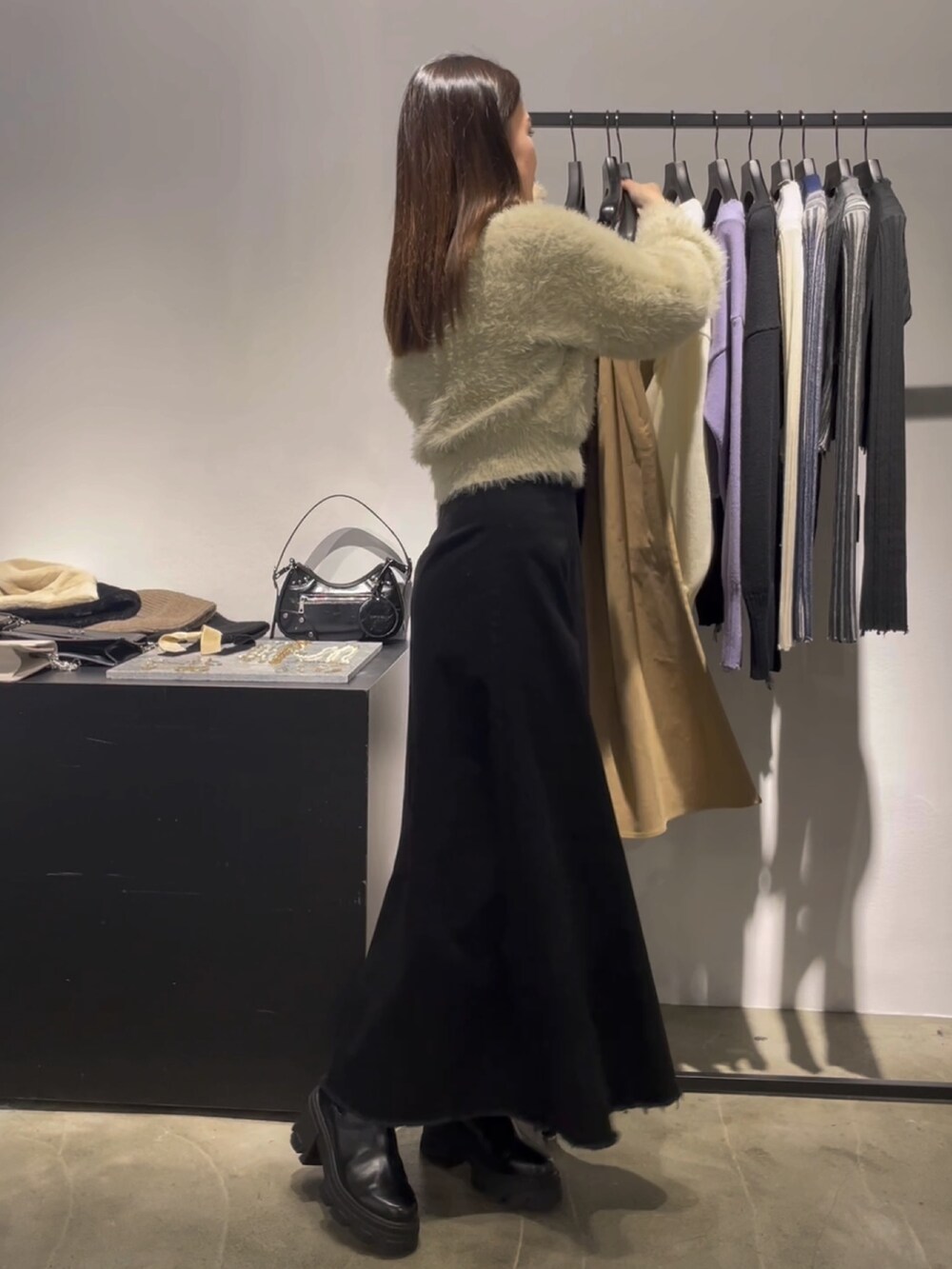 ホワイト系のニット/セーター、ブラック系のスカート、ブラック系のブーツを着用したレディースの冬コーディネートの2枚目の写真