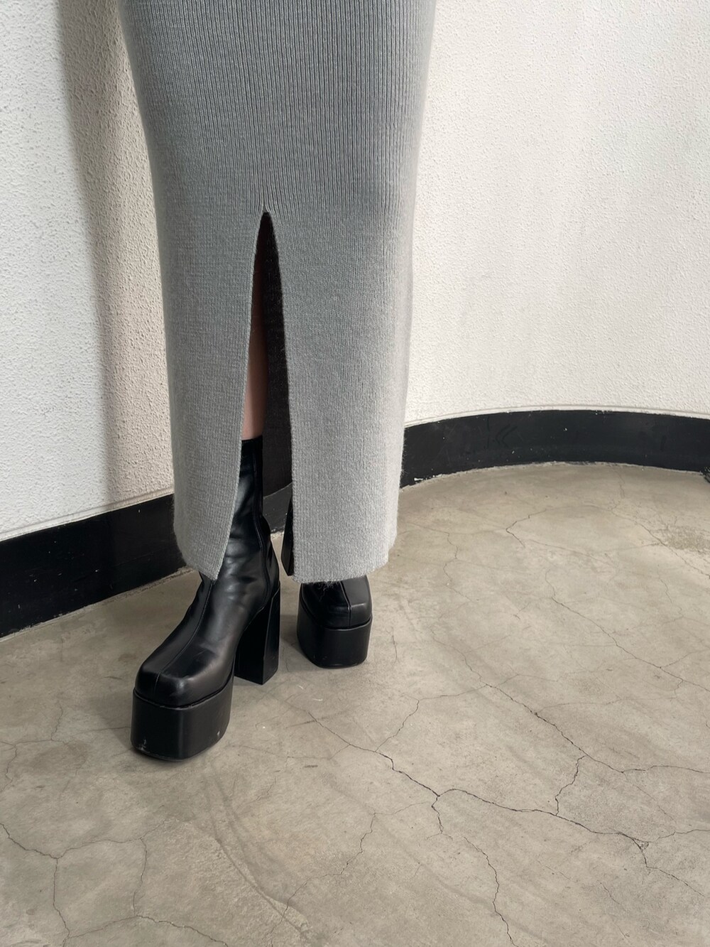 グレー系のニット/セーター、グレー系のスカート、ブラック系のブーツを着用したレディースの冬コーディネートの7枚目の写真