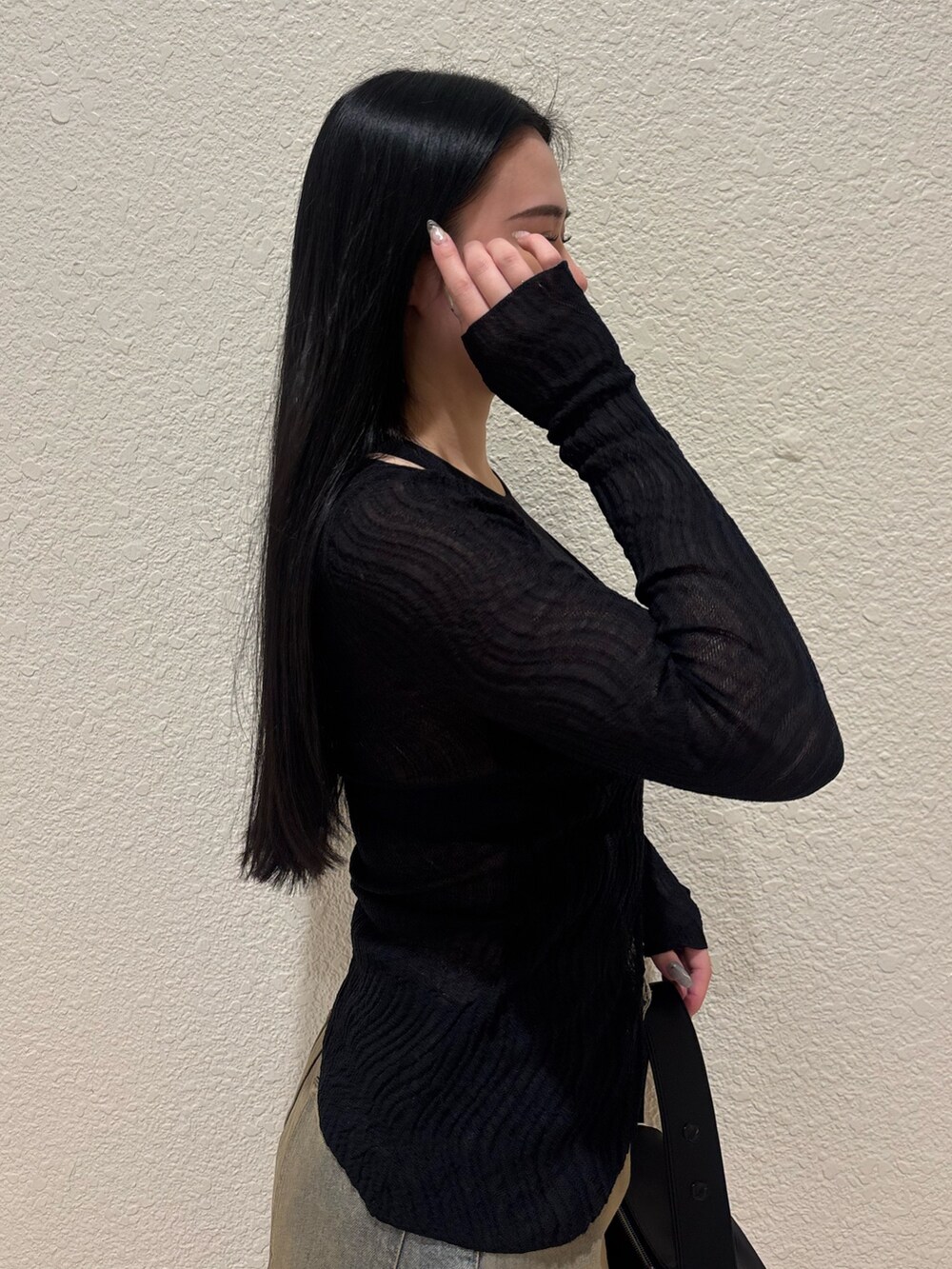 ブラック系のブーツ、ブラック系のハンドバッグ、ブルー系のデニムパンツを着用したレディースの春コーディネートの5枚目の写真