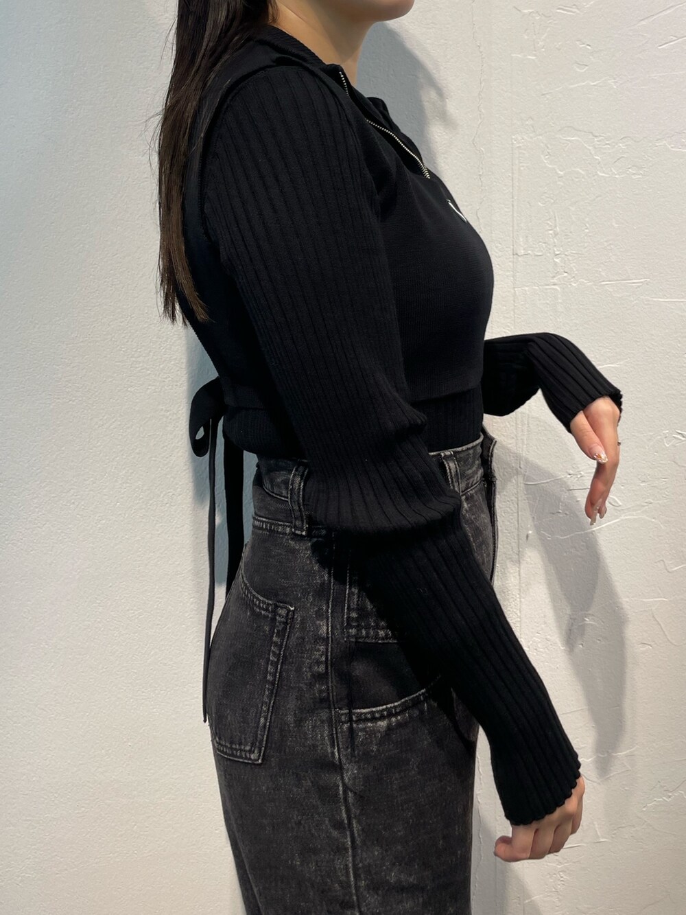 ブラック系のデニムパンツ、ブラック系のニット/セーター、シルバー系のブーツを着用したレディースの秋コーディネートの6枚目の写真