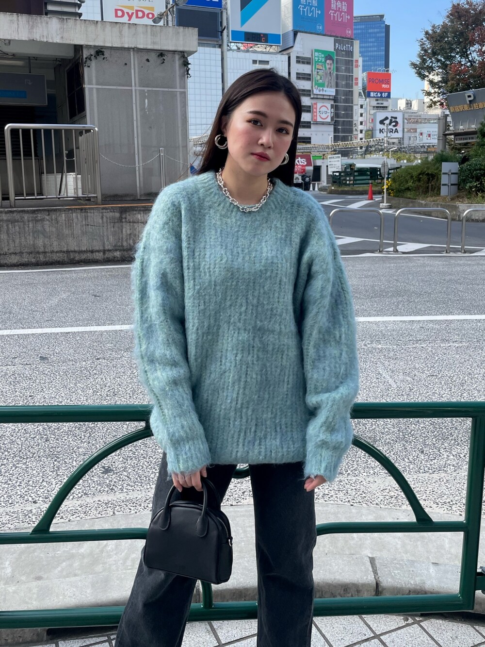 ブルー系のニット/セーター、ブラック系のデニムパンツ、ブラック系のブーツを着用したレディースの秋コーディネートの4枚目の写真