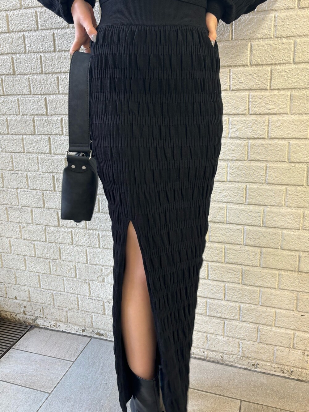 ブラック系のニット/セーター、ブラック系のスカート、ブラック系のショルダーバッグを着用したレディースの冬コーディネートの5枚目の写真