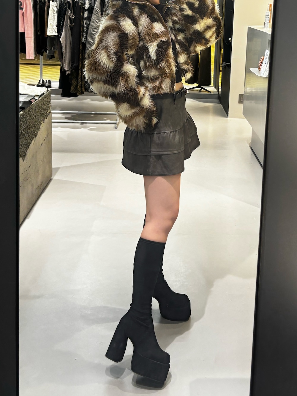 ブラック系のスカート、ブラック系のブーツ、ブラウン系のブルゾンを着用したレディースの秋コーディネートの2枚目の写真