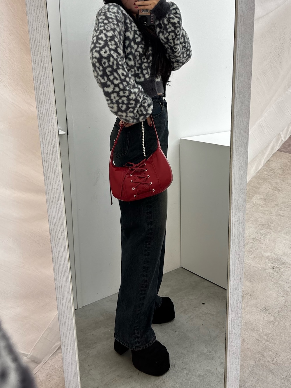 ブラック系のブーツ、ブルー系のデニムパンツ、レッド系のショルダーバッグを着用したレディースの秋コーディネートの2枚目の写真