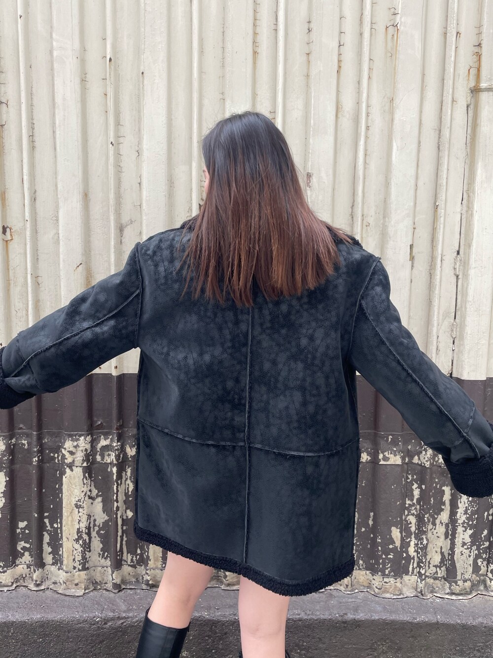 ブラック系のムートンコート、ブラック系のスカート、ホワイト系のブーツを着用したレディースの冬コーディネートの6枚目の写真