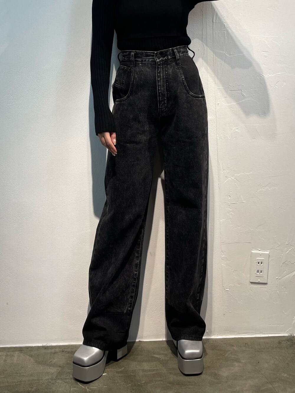 ブラック系のデニムパンツ、ブラック系のニット/セーター、シルバー系のブーツを着用したレディースの秋コーディネートの4枚目の写真