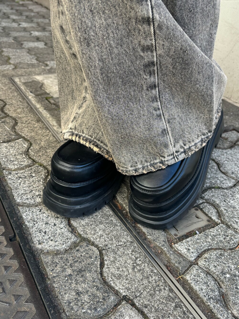 グレー系のその他アウター、ブラック系のニット/セーター、ブラック系のハンドバッグを着用したレディースの冬コーディネートの7枚目の写真