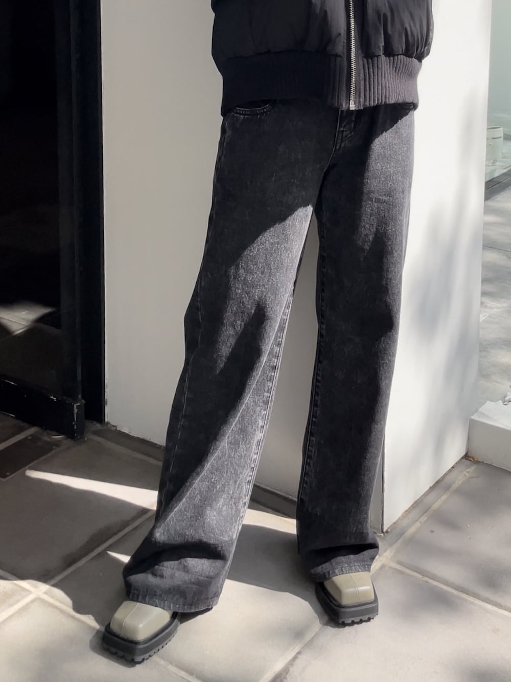 ブラック系のデニムパンツ、ブラック系のブーツ、ホワイト系のTシャツ/カットソーを着用したレディースの秋コーディネートの4枚目の写真