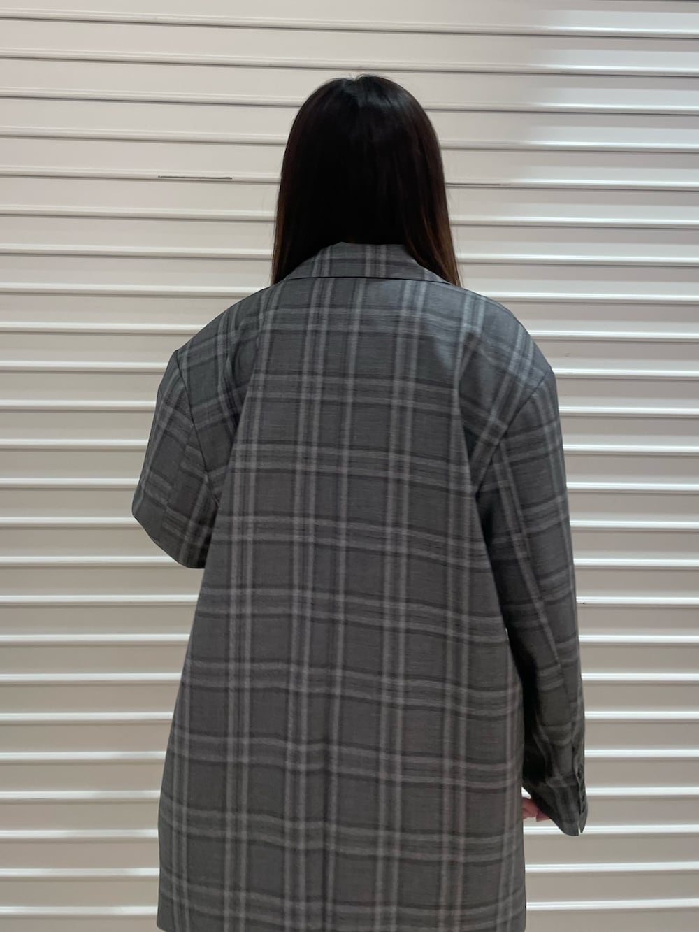 ブラック系のテーラードジャケット、ブルー系のニット/セーター、ブルー系のデニムパンツを着用したレディースの春コーディネートの6枚目の写真