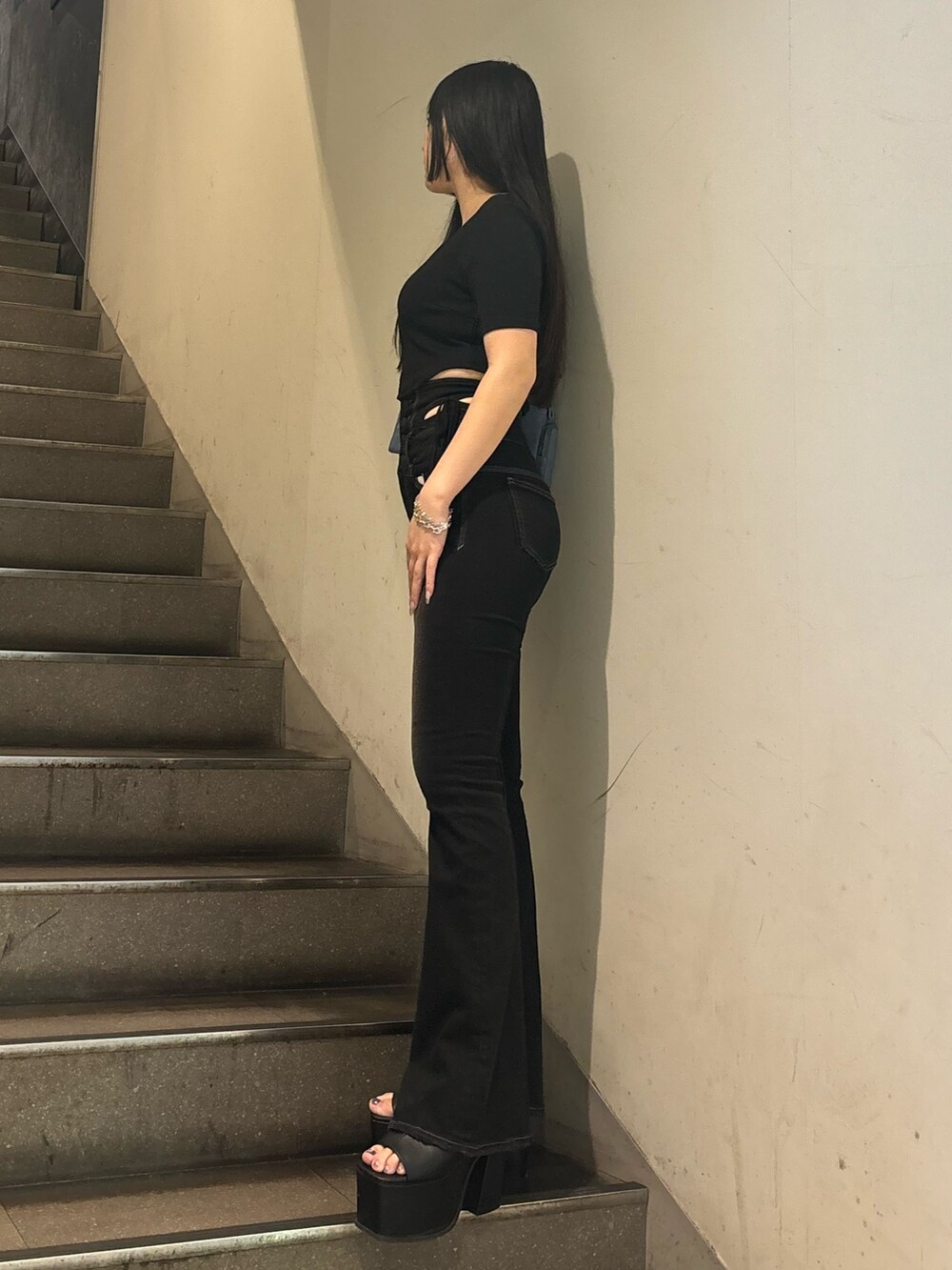 ブラック系のデニムパンツ、ホワイト系のサンダル、ブラック系のTシャツ/カットソーを着用したレディースの夏コーディネートの3枚目の写真