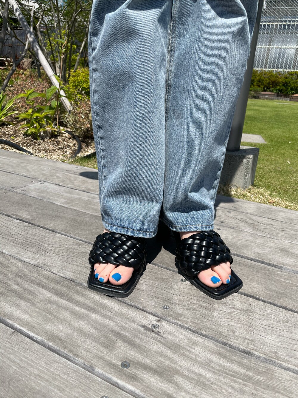 ブラック系のサンダル、ブルー系のデニムパンツ、オレンジ系のTシャツ/カットソーを着用したレディースの春コーディネートの5枚目の写真