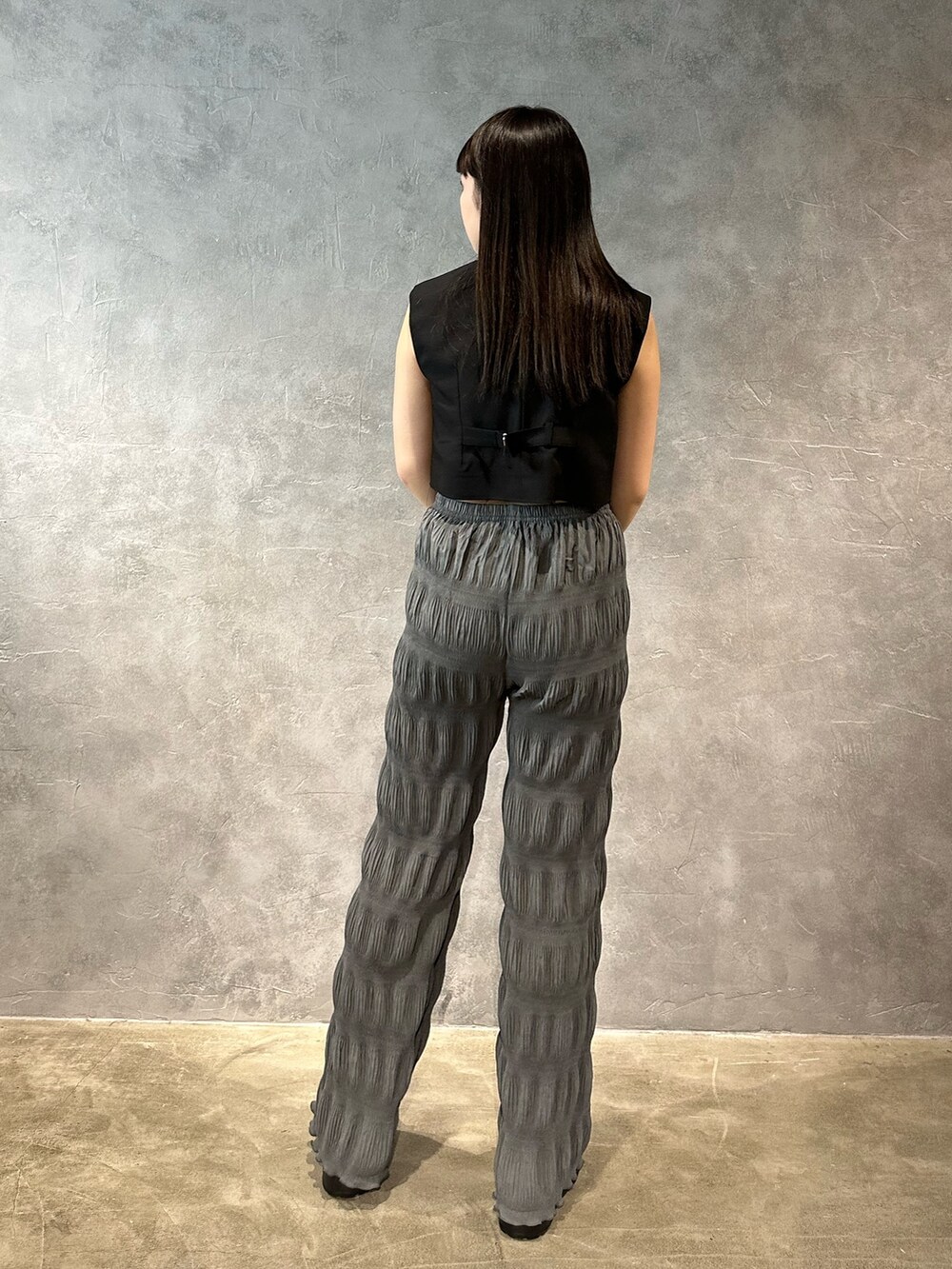 グレー系のその他パンツ、ブラック系のベスト、ブルー系のキャミソールを着用したレディースの春コーディネートの3枚目の写真