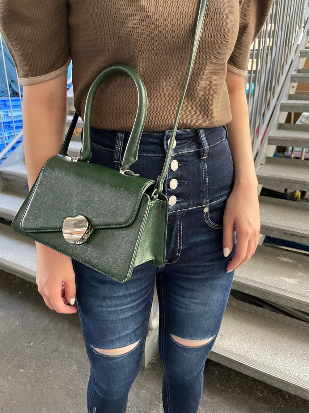 グリーン系のハンドバッグ、ベージュ系のTシャツ/カットソー、ブラック系のサンダルを着用したレディースの夏コーディネートの5枚目の写真