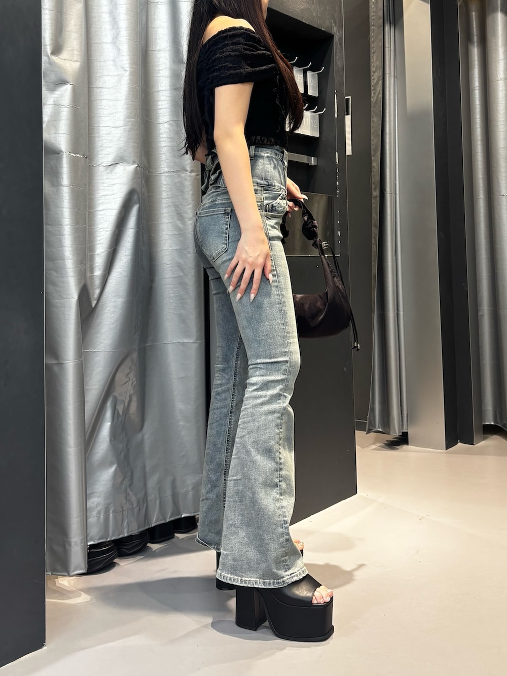 ホワイト系のサンダル、ブルー系のデニムパンツ、ブラウン系のショルダーバッグを着用したレディースの夏コーディネートの2枚目の写真