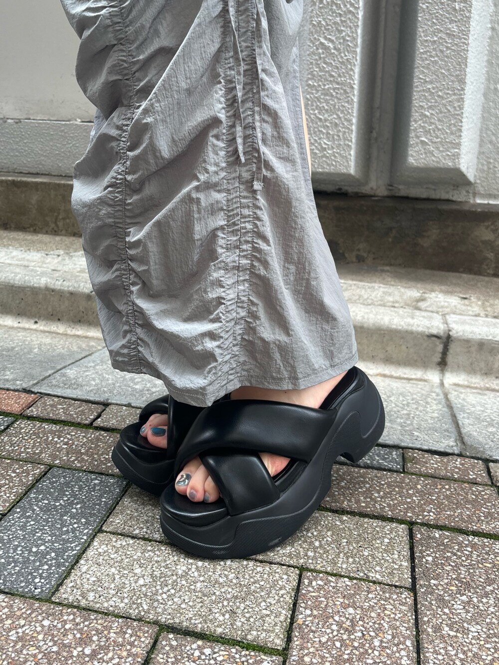 ブラック系のサンダル、ホワイト系のTシャツ/カットソー、ブラック系のハンドバッグを着用したレディースの夏コーディネートの9枚目の写真