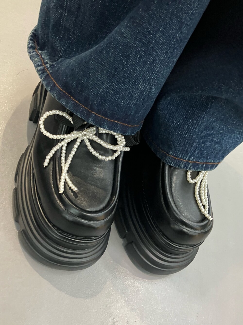 ブラック系のハンドバッグ、ブルー系のデニムパンツ、ベージュ系のブルゾンを着用したレディースの秋コーディネートの5枚目の写真