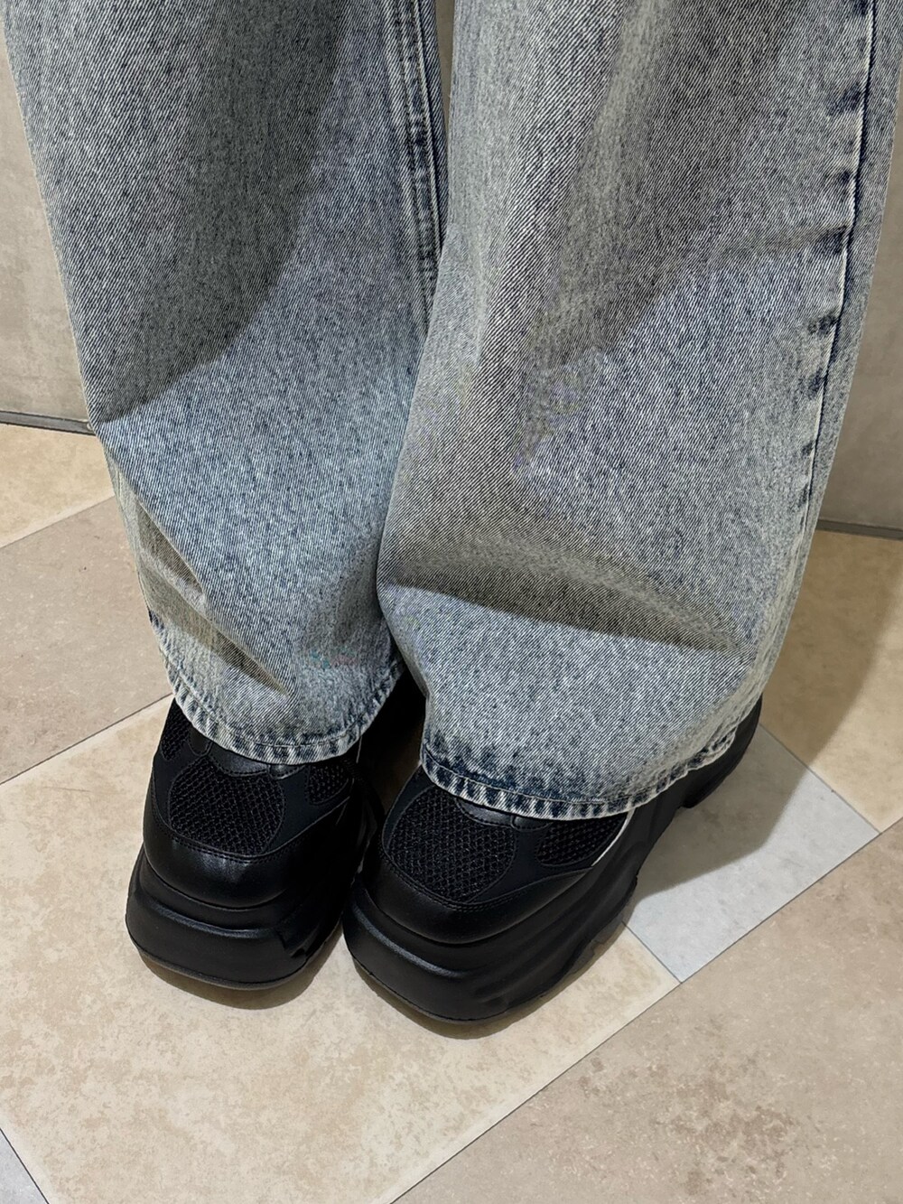 ブラック系のスニーカー、ブルー系のデニムパンツ、ブラック系のニット/セーターを着用したレディースの夏コーディネートの5枚目の写真