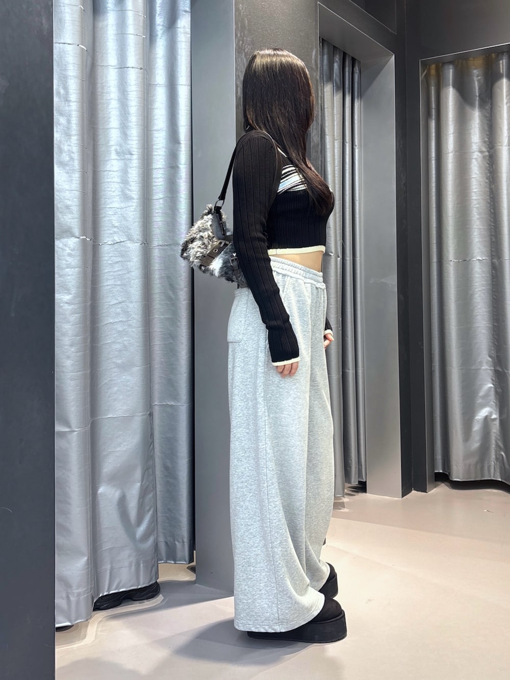 ブラウン系のショルダーバッグ、ブラック系のスリッポン、ブラック系のスウェットパンツを着用したレディースの秋コーディネートの3枚目の写真