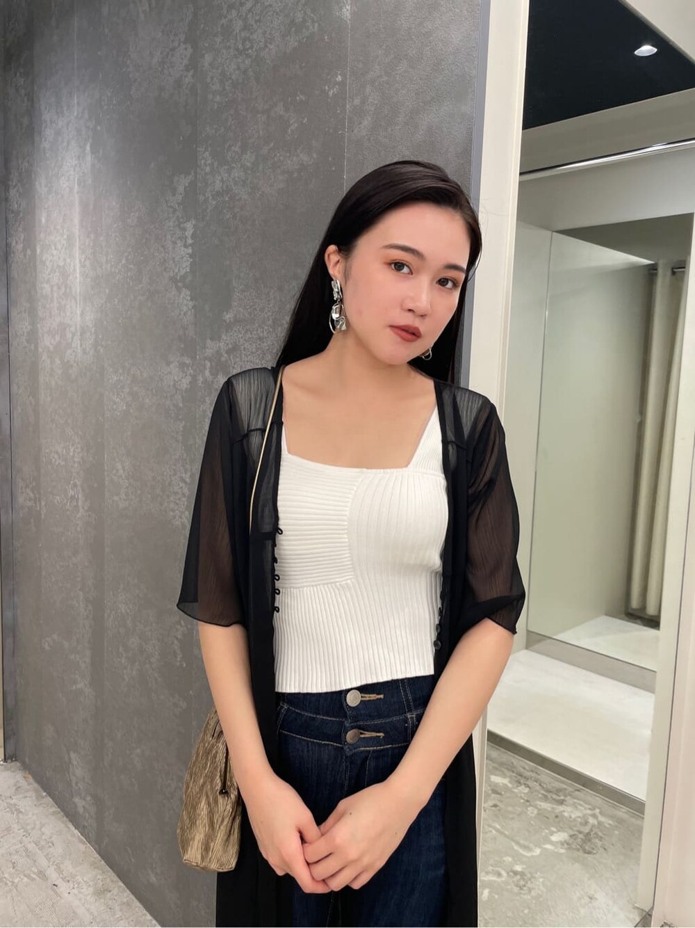 ブラック系のシャツ/ブラウス、ベージュ系のハンドバッグ、ホワイト系のニット/セーターを着用したレディースの夏コーディネートの4枚目の写真