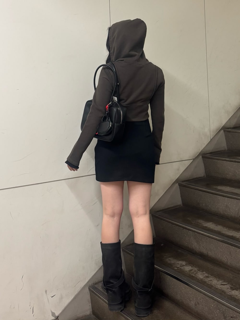 ブラック系のスカート、ブラック系のブーツ、ブラック系のハンドバッグを着用したレディースの春コーディネートの2枚目の写真