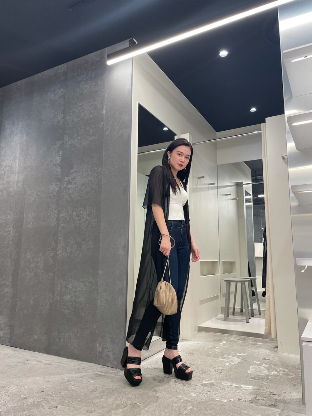 ブラック系のシャツ/ブラウス、ベージュ系のハンドバッグ、ホワイト系のニット/セーターを着用したレディースの夏コーディネートの2枚目の写真