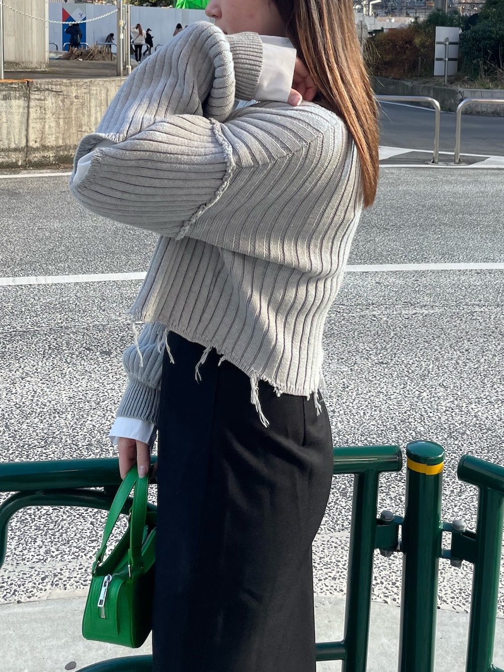 グレー系のニット/セーター、ブラック系のスカート、グリーン系のハンドバッグを着用したレディースの冬コーディネートの5枚目の写真