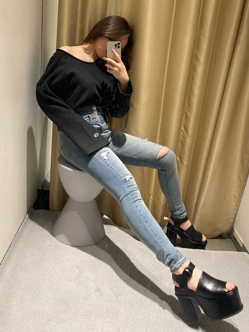 ブルー系のデニムパンツ、ブラック系のサンダル、ブラック系のTシャツ/カットソーを着用したレディースの春コーディネートの2枚目の写真