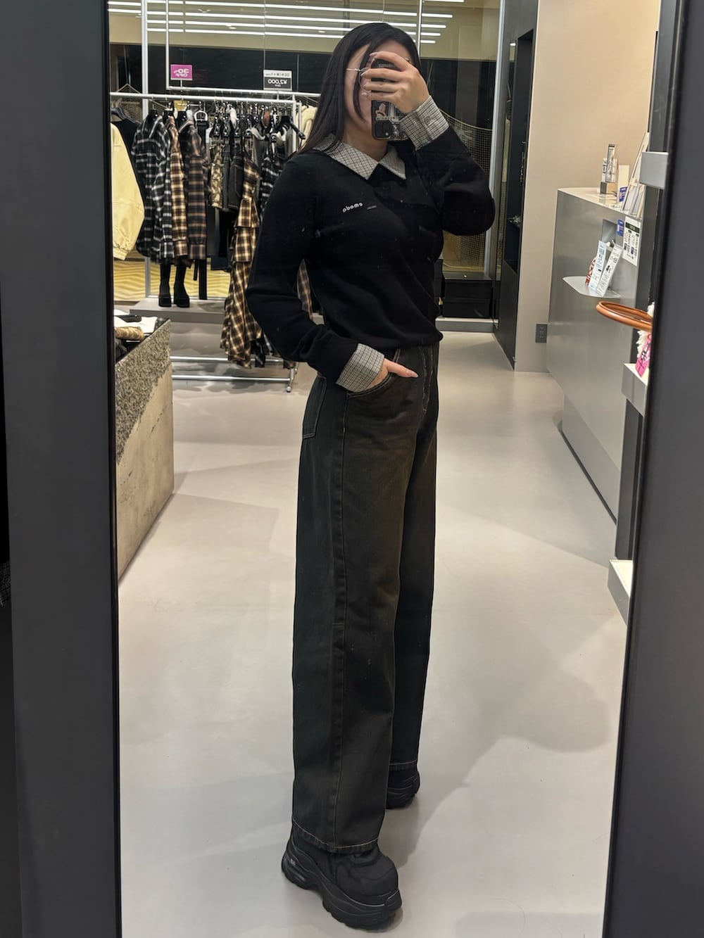 ベージュ系のデニムパンツ、ブラック系のシャツ/ブラウス、ブラック系のスニーカーを着用したレディースの冬コーディネートの2枚目の写真