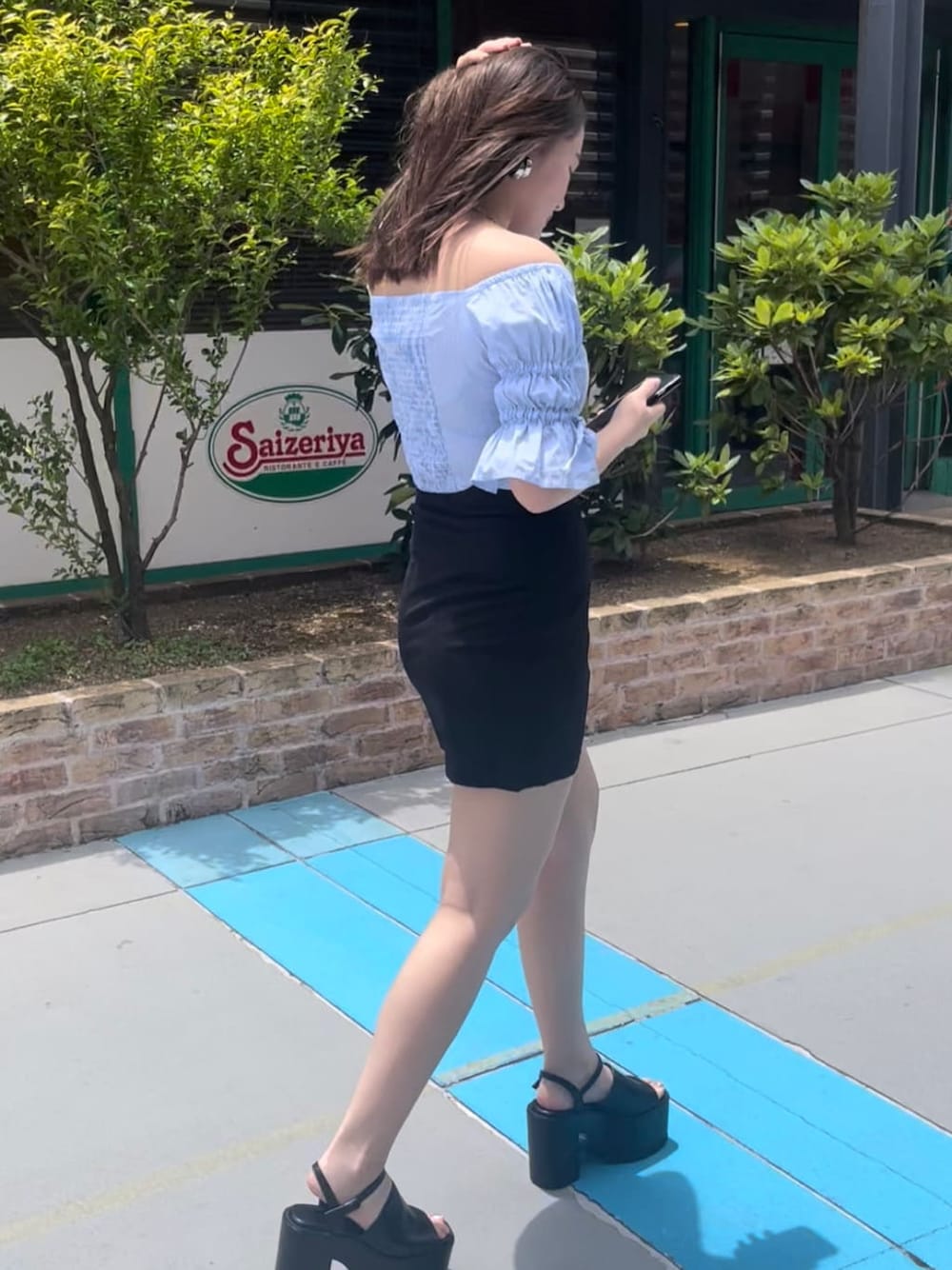 ブラック系のスカート、ブラック系のサンダル、ブルー系のシャツ/ブラウスを着用したレディースの夏コーディネートの2枚目の写真