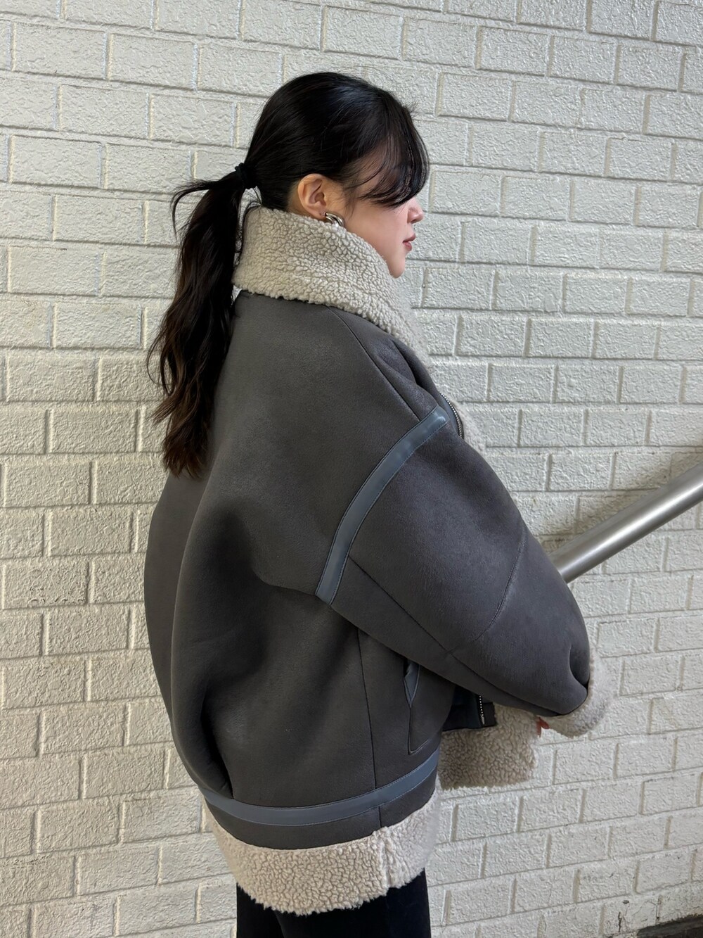 グレー系のムートンコート、ブラック系のデニムパンツ、その他のブーツを着用したレディースの秋コーディネートの5枚目の写真