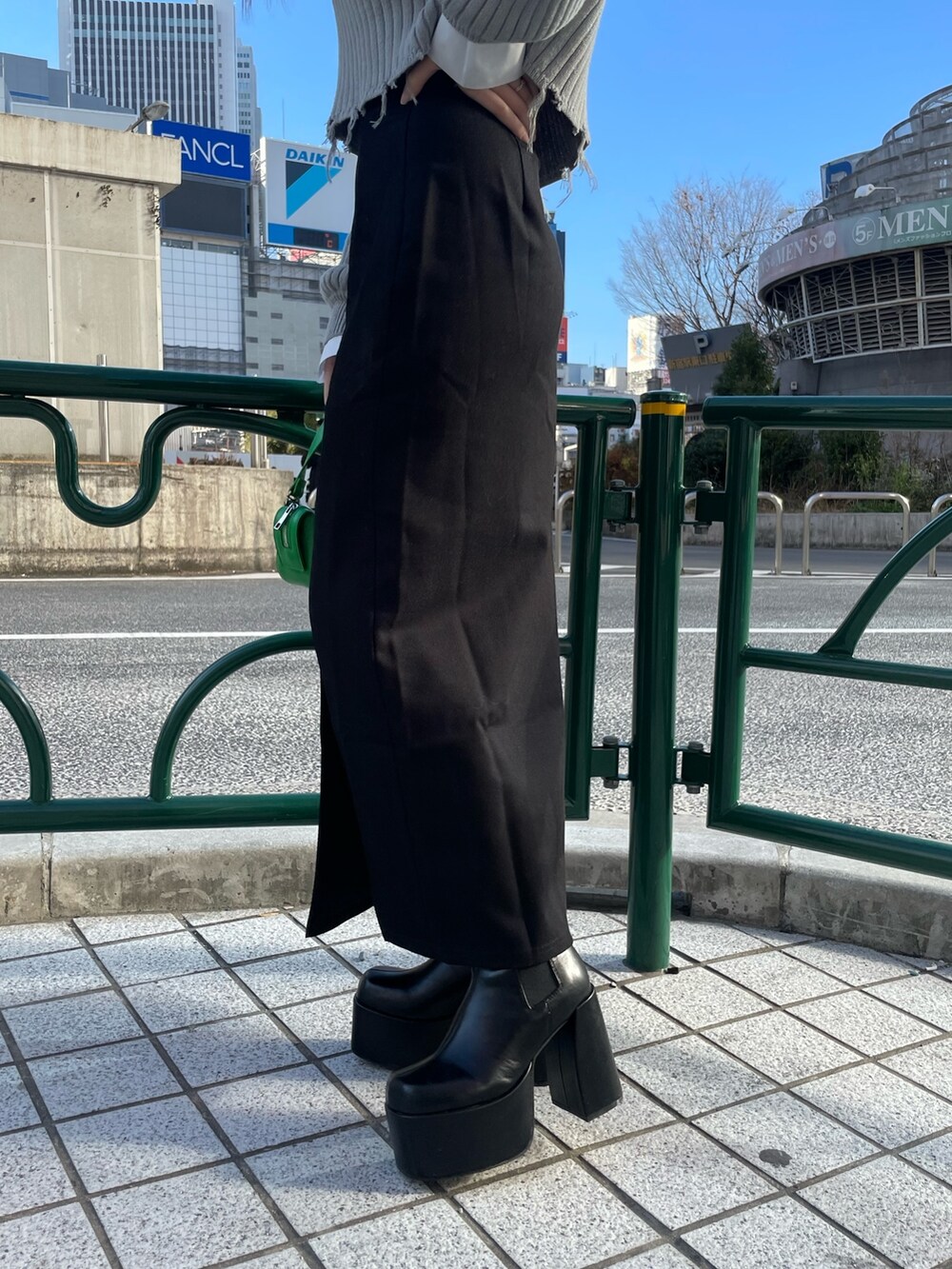 グレー系のニット/セーター、ブラック系のスカート、グリーン系のハンドバッグを着用したレディースの冬コーディネートの8枚目の写真