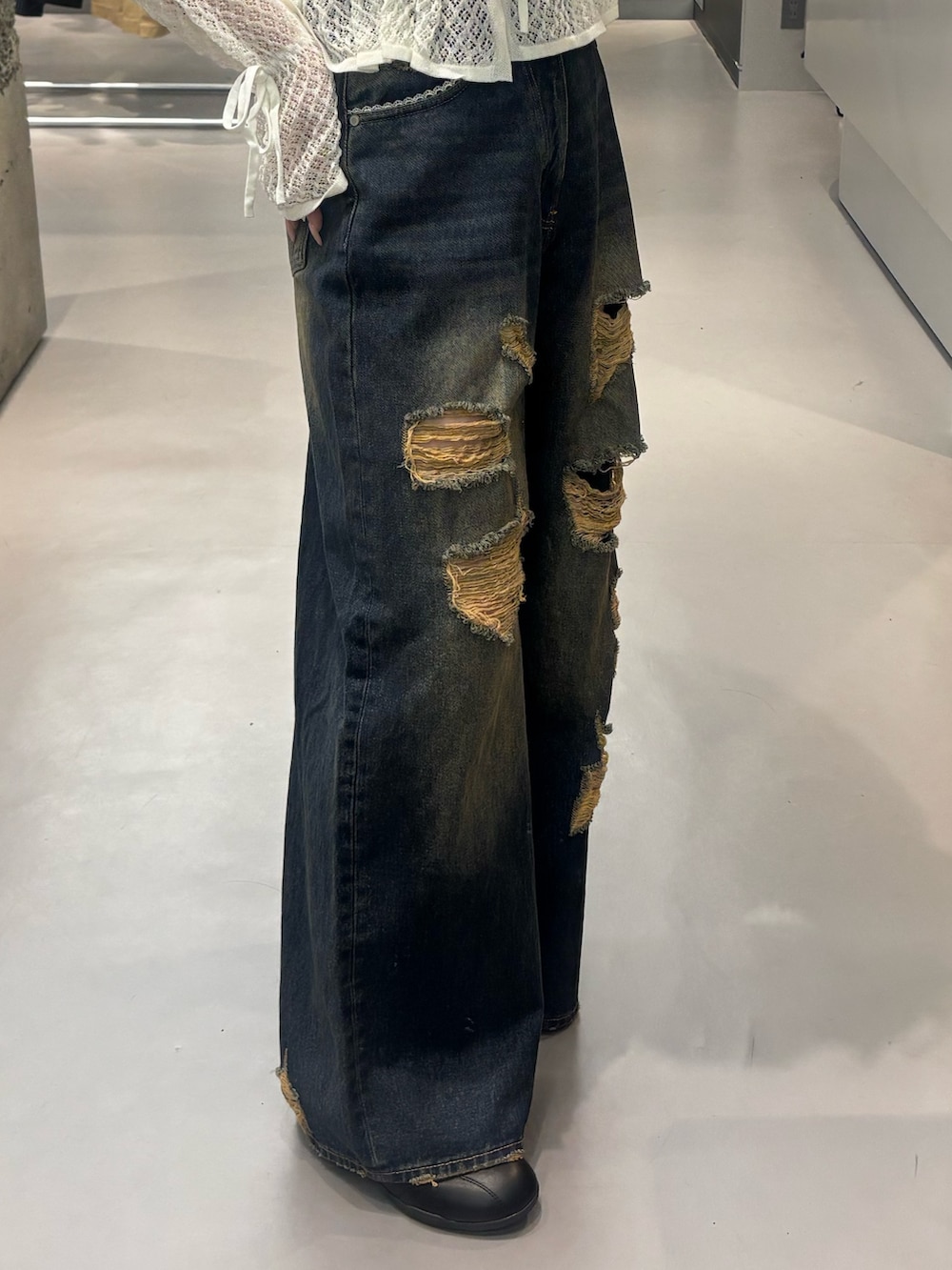 ブラック系のスニーカー、ブルー系のデニムパンツ、ホワイト系のニット/セーターを着用したレディースの春コーディネートの5枚目の写真