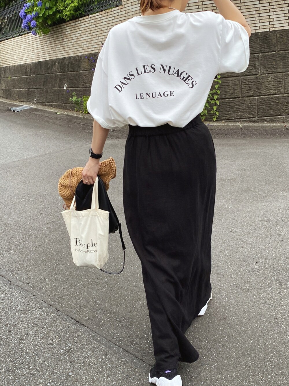 ホワイト系のTシャツ/カットソー、ブラック系のスカート、ブラック系のスニーカーを着用したレディースの夏コーディネートの2枚目の写真