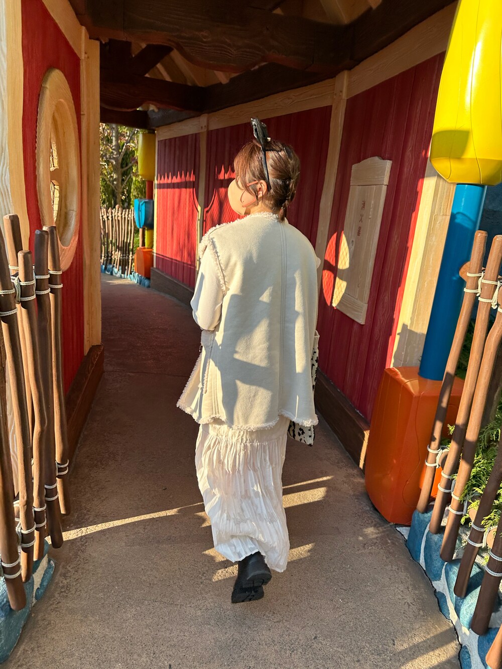 ブラック系のブーツ、ホワイト系のトップス、ホワイト系のベストを着用したレディースの春コーディネートの2枚目の写真