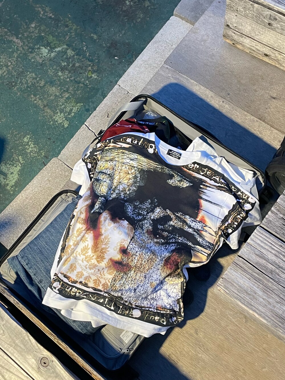 ブルー系のトートバッグ、ブルー系のデニムパンツ、ホワイト系のトップスを着用したメンズの夏コーディネートの2枚目の写真