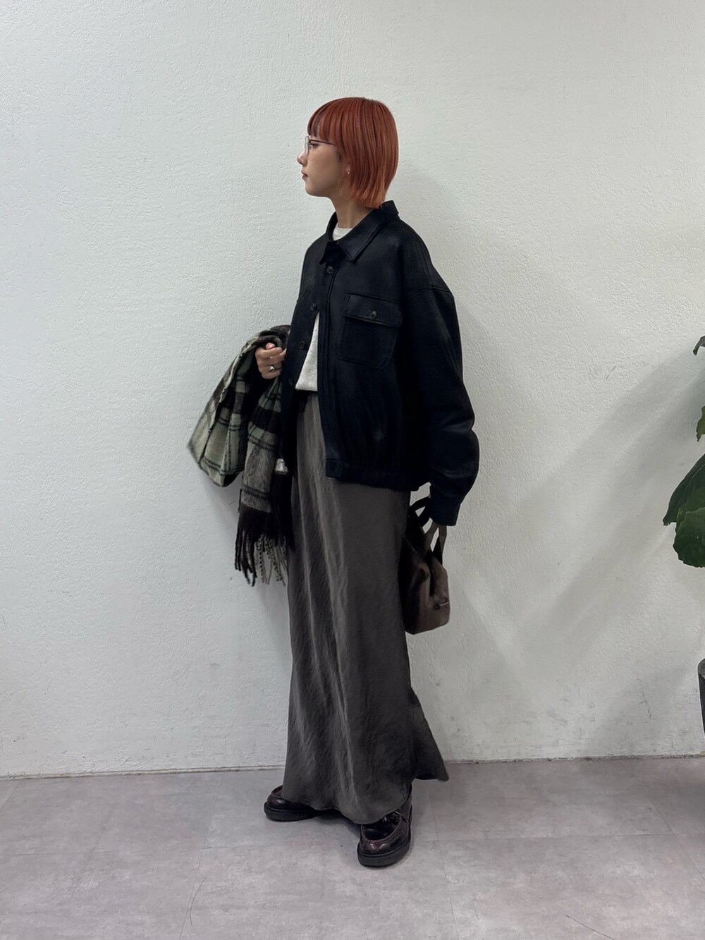 ブラック系のブルゾン、ホワイト系のニット/セーター、グレー系のスカートを着用したレディースの秋コーディネートの2枚目の写真