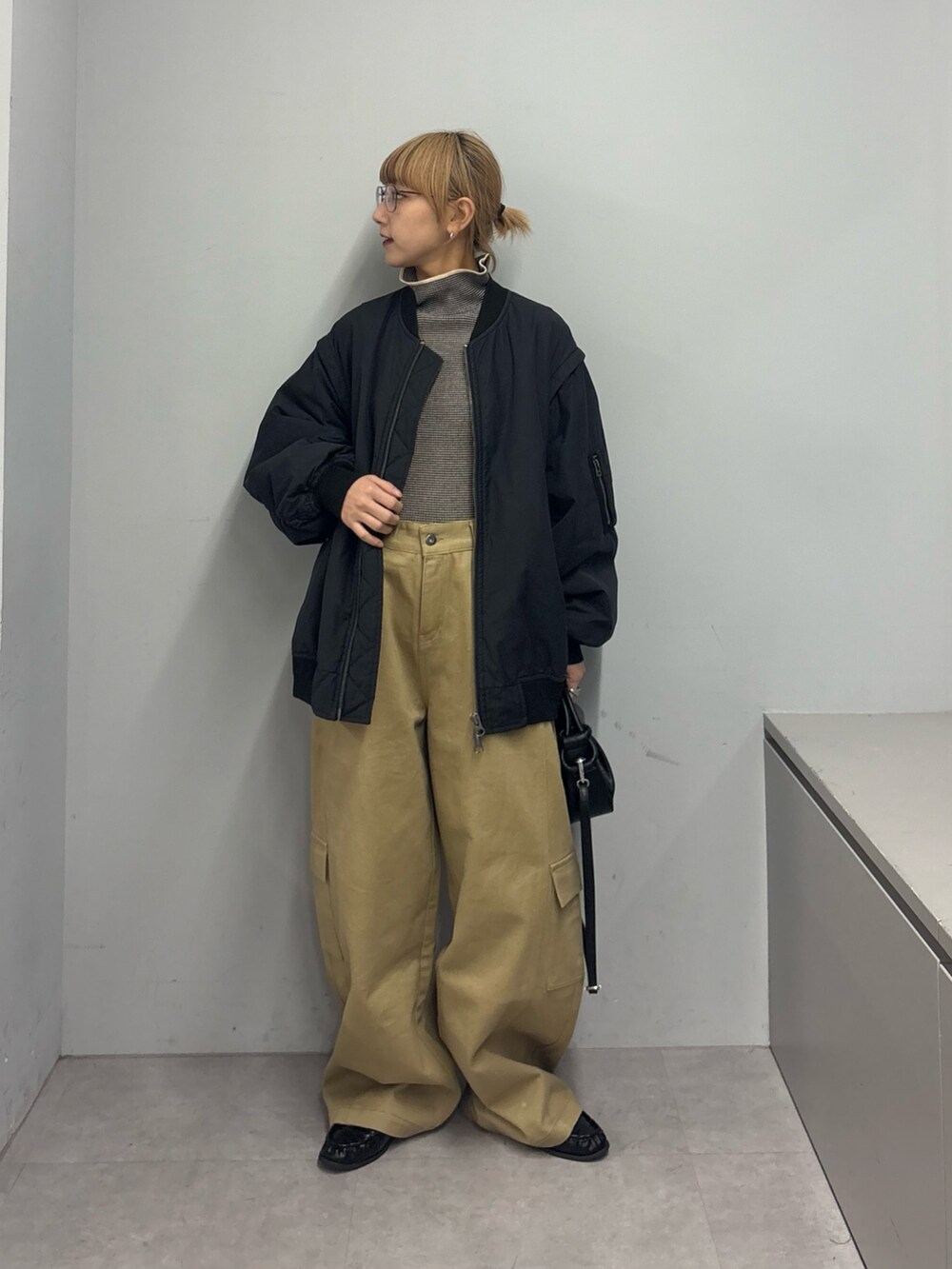 ブラック系のMA-1、ホワイト系のニット/セーター、ベージュ系のカーゴパンツを着用したレディースの冬コーディネートの2枚目の写真