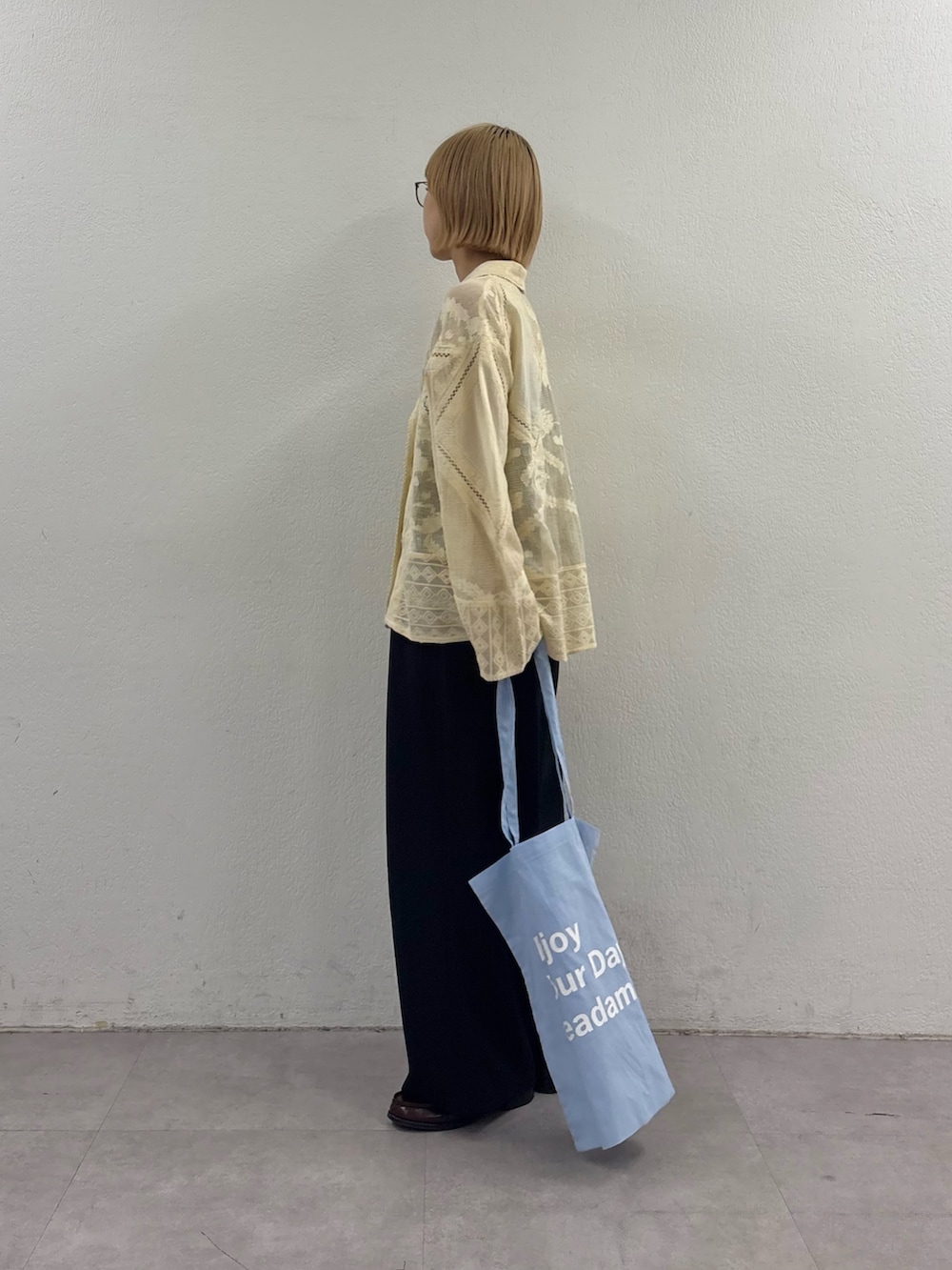 イエロー系のシャツ/ブラウス、ブルー系のトートバッグ、ブラック系のスラックスを着用したレディースの春コーディネートの3枚目の写真