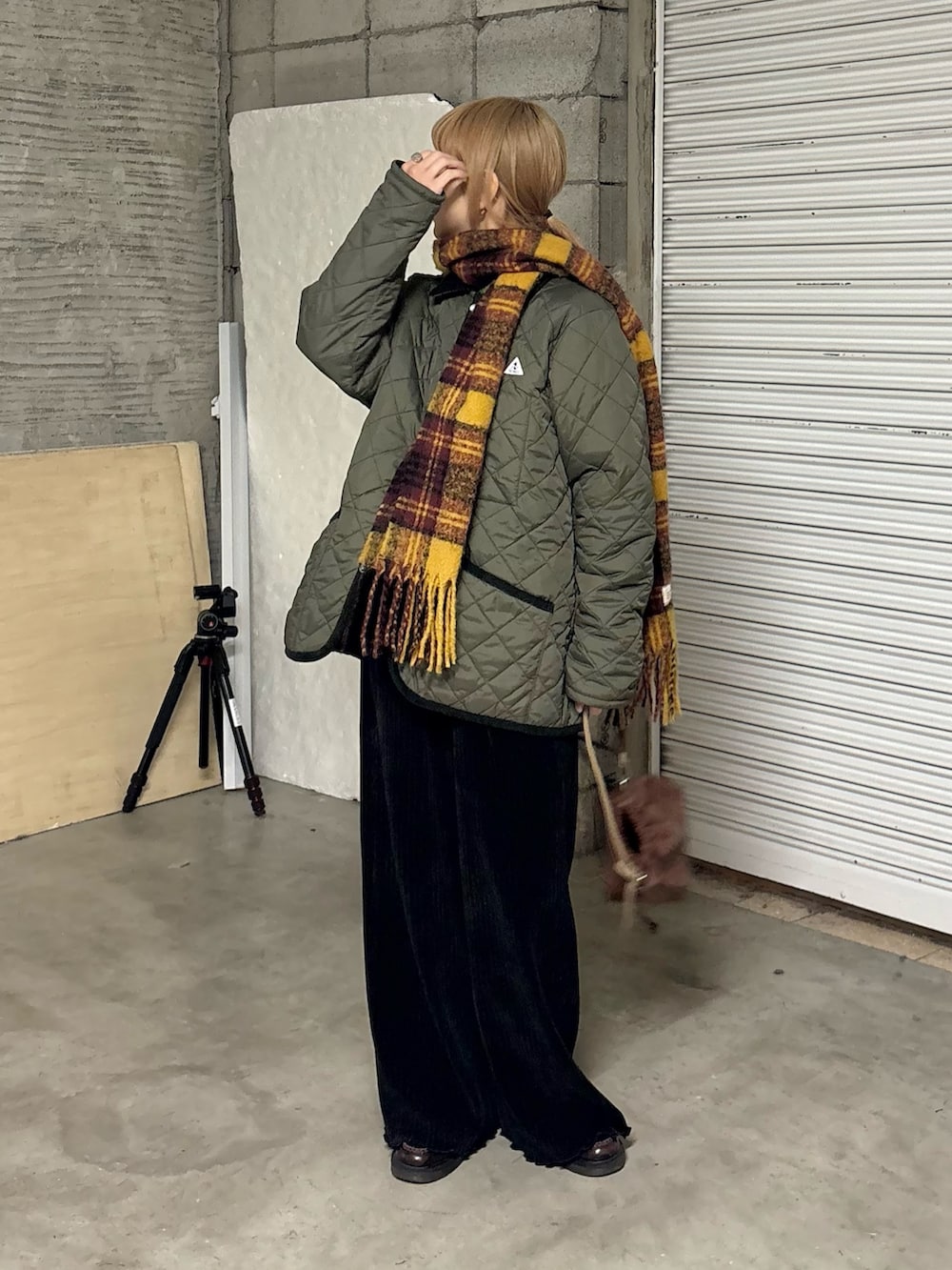 グリーン系のブルゾン、ブラック系のその他パンツ、ブラウン系のショルダーバッグを着用したレディースの冬コーディネートの2枚目の写真