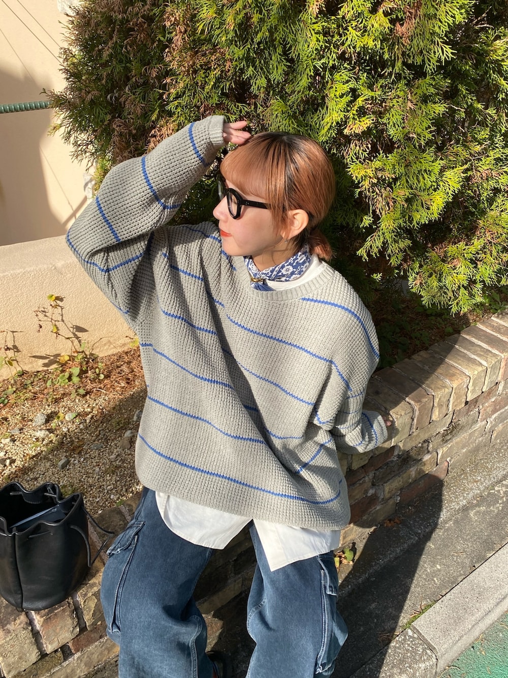 グレー系のニット/セーター、ホワイト系のシャツ/ブラウス、ブラック系のハンドバッグを着用したレディースの冬コーディネートの2枚目の写真