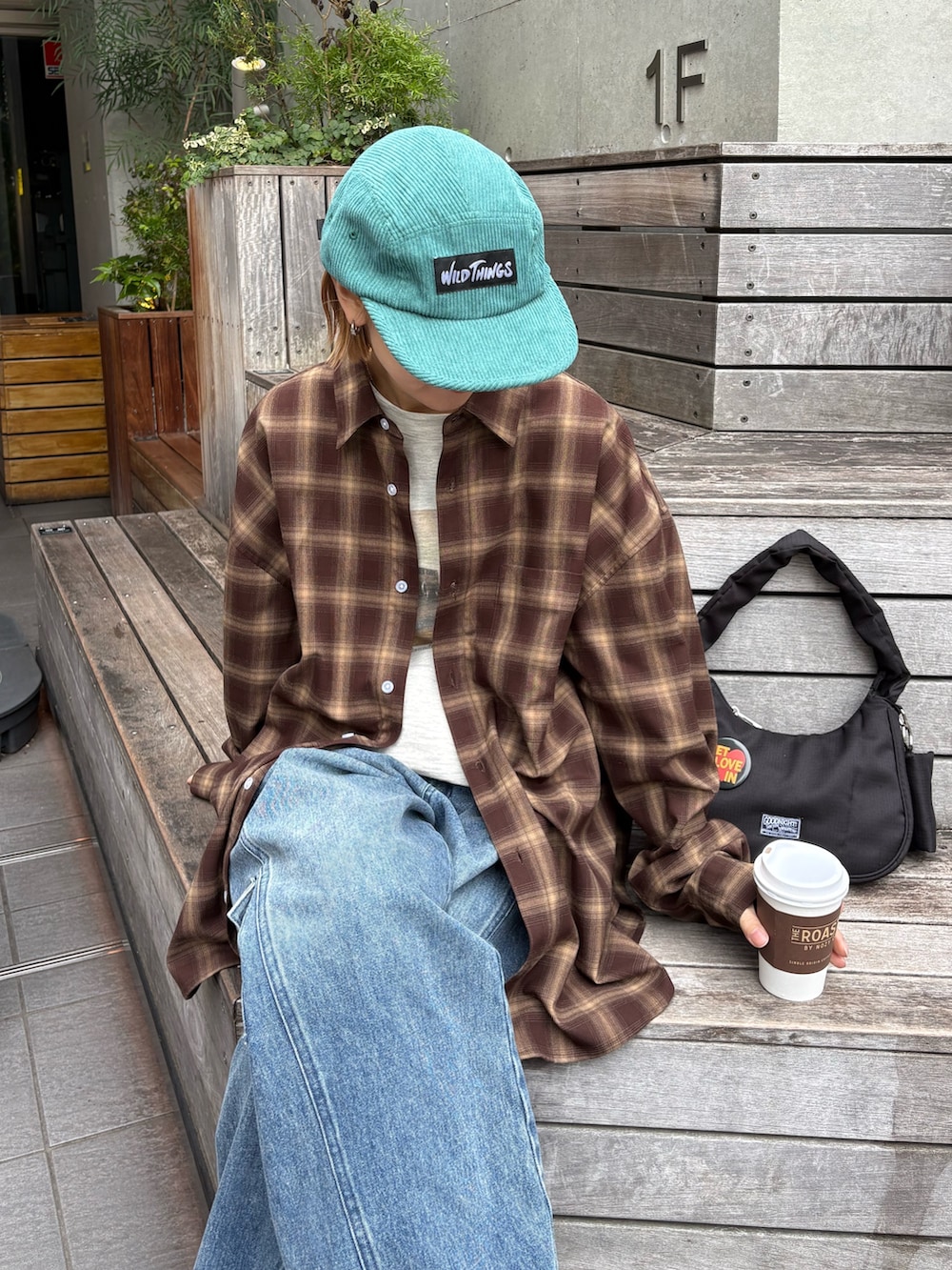 ブラック系のショルダーバッグ、ブラウン系のシャツ/ブラウス、グレー系のTシャツ/カットソーを着用したレディースの春コーディネートの2枚目の写真