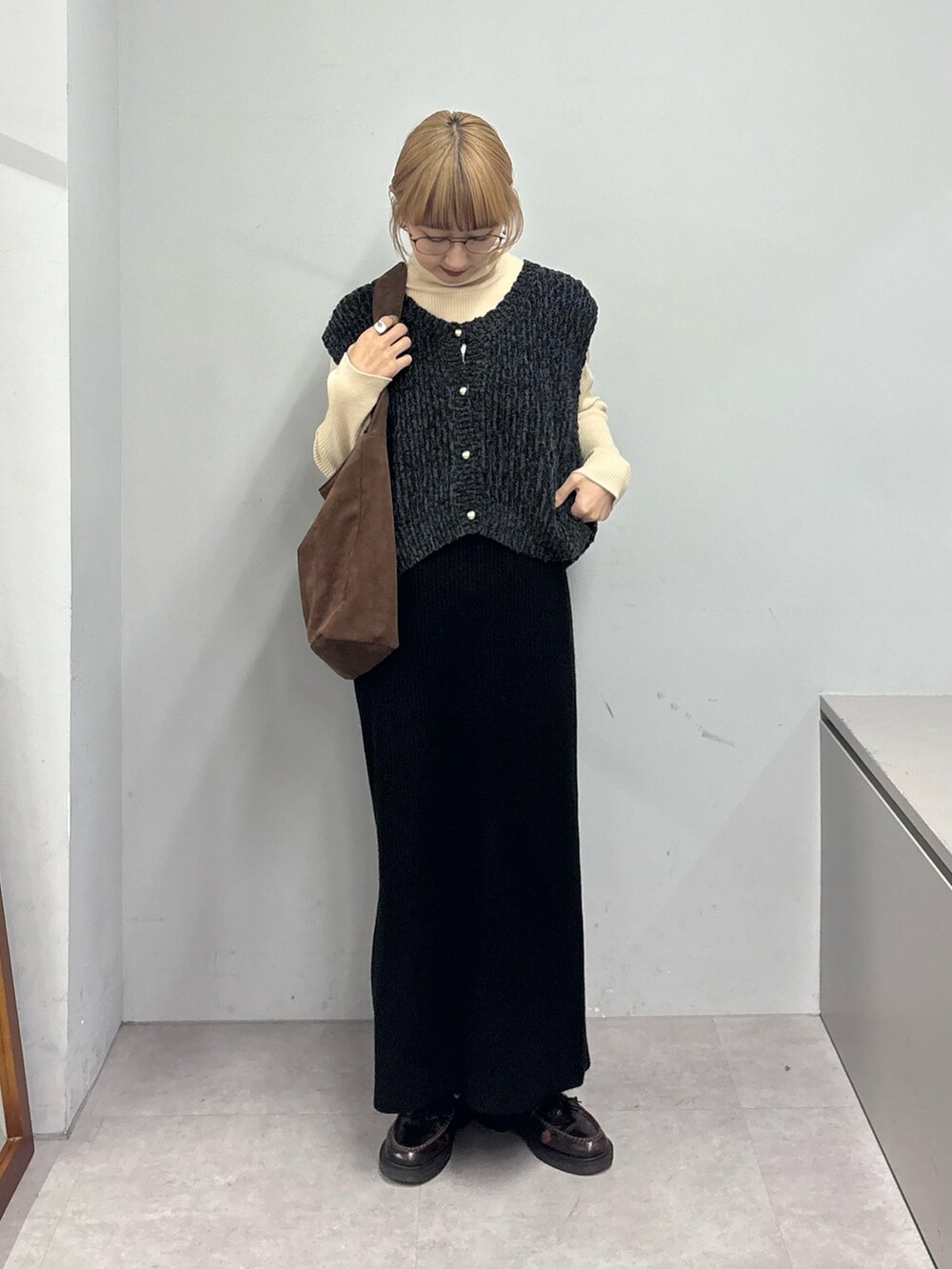 ホワイト系のニット/セーター、ブラック系のベスト、ブラック系のスカートを着用したレディースの冬コーディネートの2枚目の写真