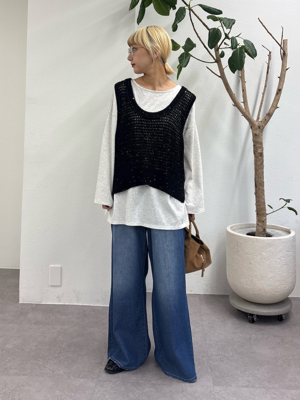 ブラック系のベスト、グレー系のTシャツ/カットソー、ブルー系のデニムパンツを着用したレディースの春コーディネートの2枚目の写真